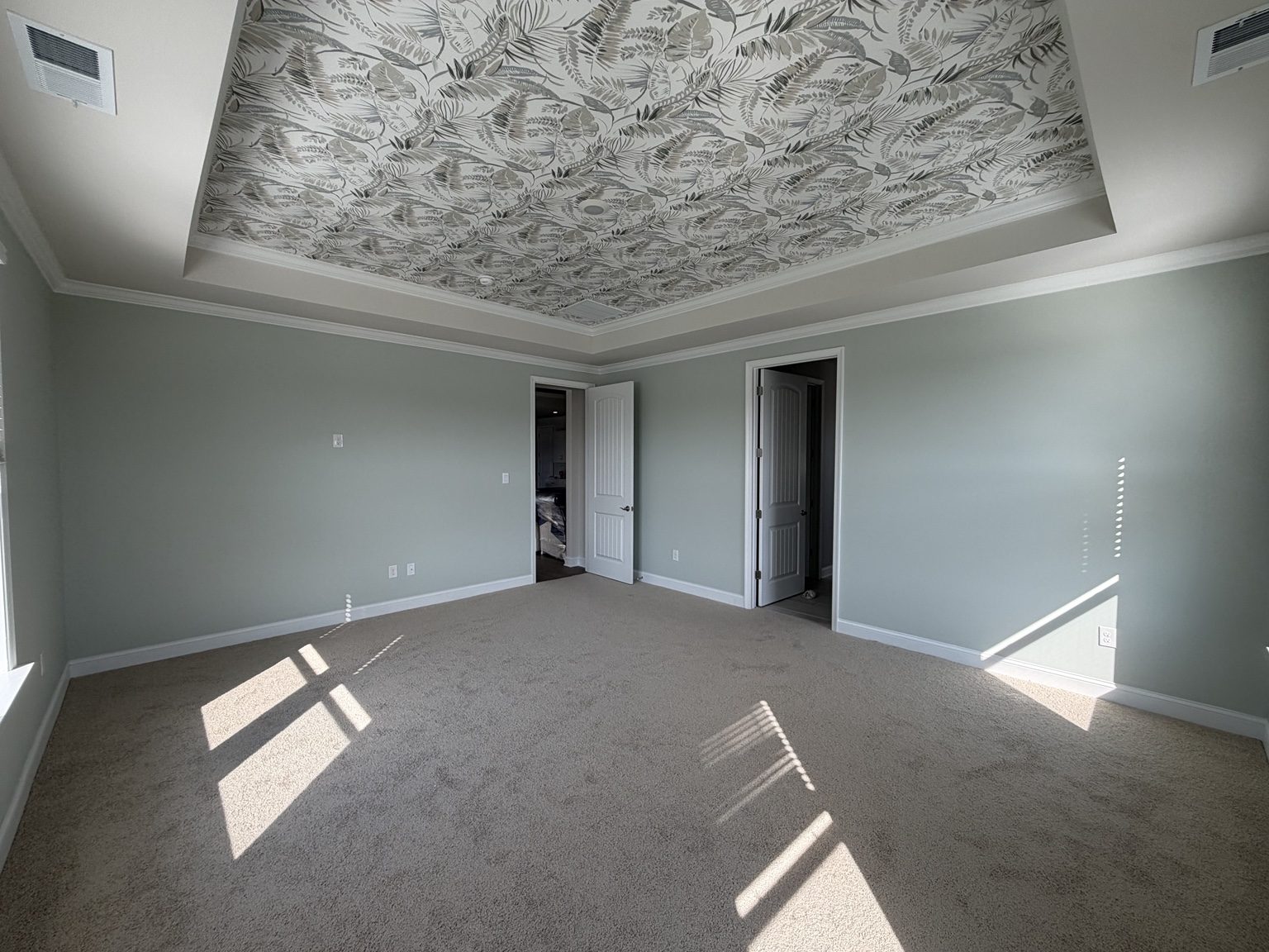 Freshly painted master bedroom with a wallpapered tray ceiling and sage green walls